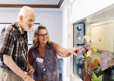 Employee at Lindstrom Senior Living spending time by the fish tank with a resident male