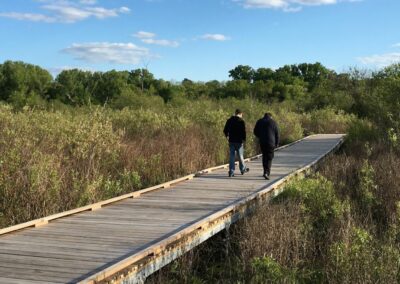 senior husband and wife walking dog on a boardwalk