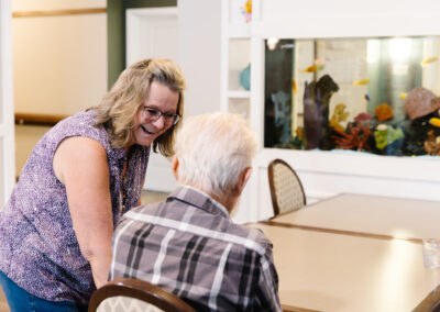 Employee at Lindstrom Senior Living spending time by the fish tank with a resident male